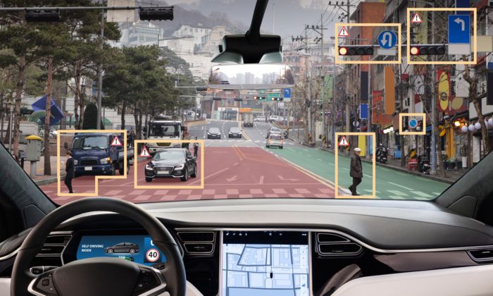 A view of a street from the viewpoint of a car driver, with the front window showing shapes around objects of interest, such as other cars and humans